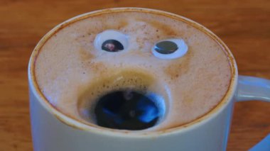 Close-up coffee cup with eyes and mouth screaming very loudly. Emoji coffee. Cheerful mood of the barista who made coffee with a human face. High quality 4k footage