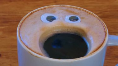 Close-up coffee cup with eyes and mouth screaming very loudly. Emoji coffee. Cheerful mood of the barista who made coffee with a human face. High quality 4k footage