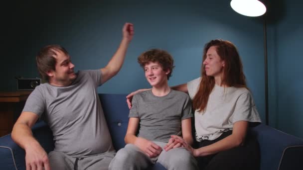 Fürsorgliche Eltern Sitzen Mit Ihrem Halbwüchsigen Sohn Auf Einem Blauen — Stockvideo