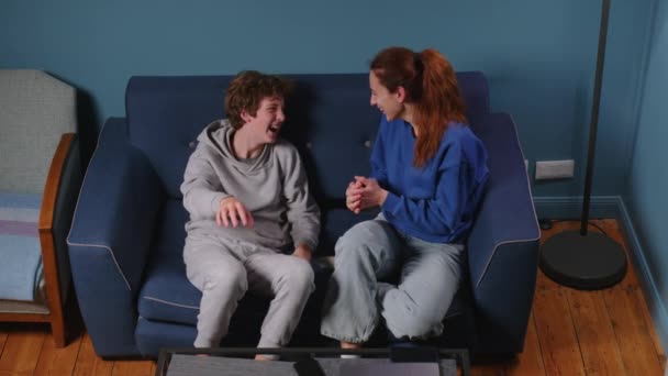 一个由母亲和儿子组成的家庭 坐在美丽的室内蓝色沙发上 心情愉快地笑着 青少年的对话和教育 良好的家庭关系 — 图库视频影像