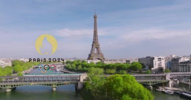 Paris, Fransa, 06 Nisan 2023: Paris 2024 Olimpiyat Oyunları 'nın logosu Eyfel Kulesi yakınlarındaki ünlü köprünün üzerinden geçen yeşil bir metro treninde. Fransa 'nın başkentine insansız hava aracı.
