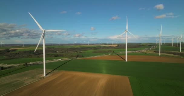 風力発電機は緑のフィールドで回転する 大規模な風力タービンフィールド空中ビュー風力公園でブレードを持つ 青空に美しい雲 フランスの緑のエネルギー 高品質4K — ストック動画
