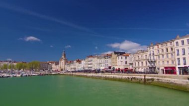 La Rochelle Fransa 'daki limanda zaman aşımı. Okyanustaki ünlü Fransız şehri. Güneşli bir yaz günü, arka planda bulutlar hareket ediyor. Turist kalabalığı sokaklarda yürüyor. Yüksek kalite 4k görüntü