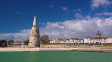 La Rochelle Fransa 'daki limanda zaman aşımı. Okyanustaki ünlü Fransız şehri. Güneşli bir yaz günü, arka planda bulutlar hareket ediyor. Turist kalabalığı sokaklarda yürüyor. Yüksek kalite 4k görüntü