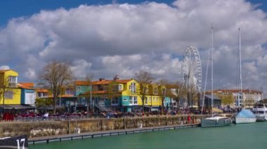 La Rochelle Fransa 'daki limanda zaman aşımı. Okyanustaki ünlü Fransız şehri. Güneşli bir yaz günü, arka planda bulutlar hareket ediyor. Turist kalabalığı sokaklarda yürüyor. Yüksek kalite 4k görüntü