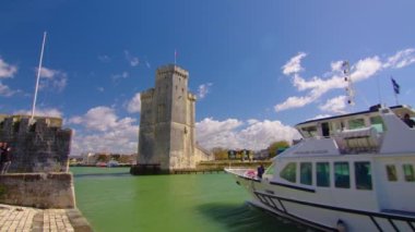 Fransa La Rochelle, 15 Nisan 2023: Okyanustaki ünlü Fransız şehri. Güneşli bir yaz günü, arka planda bulutlar hareket ediyor. Turist kalabalığı sokaklarda yürüyor. Yüksek kalite 4k görüntü
