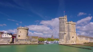 La Rochelle Fransa 'daki limanda zaman aşımı. Okyanustaki ünlü Fransız şehri. Güneşli bir yaz günü, arka planda bulutlar hareket ediyor. Turist kalabalığı sokaklarda yürüyor. Yüksek kalite 4k görüntü
