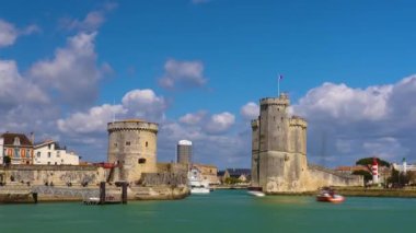 La Rochelle Fransa 'daki limanda zaman aşımı. Okyanustaki ünlü Fransız şehri. Güneşli bir yaz günü, arka planda bulutlar hareket ediyor. Turist kalabalığı sokaklarda yürüyor. Yüksek kalite 4k görüntü