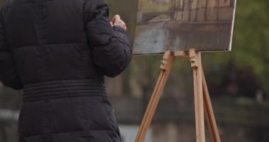 Kadın sokak ressamının Paris şehir manzarası ile eskiz çalışması var. Deneyimli Avrupalı kadın sanatçı nehir kenarında yeni bir resim çiziyor. Ressam ve onun yaşam tarzı hobisi..