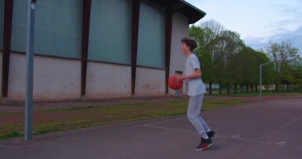 Video Niño Parado Una Cancha Baloncesto Sosteniendo Una Pelota Baloncesto — Vídeos de Stock