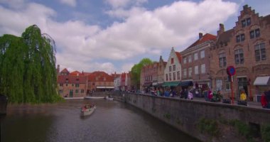 Bruges, Belçika, 26 Mayıs 2023: Şehir merkezindeki binalar. Şehirde yürüyen insanlar. İnsanlar ve turistler Pazar Meydanı 'nda yürüyorlar. Bruges Kulesi 'nin çan kulesi ve arka planda gotik binalar.