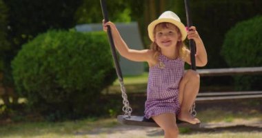 Küçük kız salıncakta sallanıyor. Lunapark rüyası konsepti. Gün batımında parkta sallanan mutlu kız. Portre çocuğu çocukluk hayaliyle oynar. Bebek parkta sallanıyor..