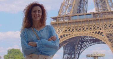 Gülümseyen turist kadın ünlü Eyfel Kulesi 'nin simgesine bakıyor. Fransa 'nın başkentinde tatilde olan bir kadın Eyfel Kulesi' nin etrafında dolaşıyor. Eyfel Kulesi en çok fotoğraflanan simgedir.