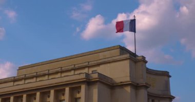 Paris 'te Eyfel Kulesi yakınlarındaki bir binanın çatısında Fransız bayrağı. Rüzgarda dalgalanan bayrak Fransa 'daki Tracadero Meydanı' nda mavi gökyüzünün arka planına karşı.