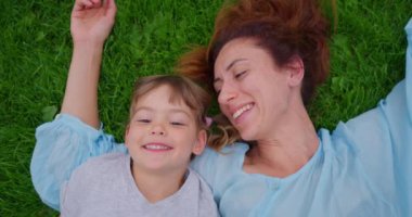 3 yaşında bir kız ve annesi parkta yeşil çimlerin üzerinde gülüyor. Yaz parkında mutlu bir aile birlikte dinleniyor. Yeni bir annesi olan evlatlık bir kız. Çocuk evlat edinme kavramı.