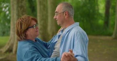 Sonbahar parkında dans eden mutlu yaşlı çift. Sonbahar kenti parkında dans eden ve gülümseyen neşeli, aktif bir kadın ve erkek portresi. Yüksek kalite 4k görüntü