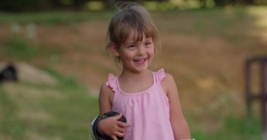 Gülümseyen güzel bir kızın portresi. Mutlu şirin çocuk yaz parkında eğleniyor, çocukluğun tadını çıkarıyor, keyifli bir ruh hali içinde. Yüksek kalite 4k görüntü