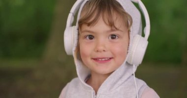 Kulaklıklı şirin bir kızın portresi. Güzel gülümseyen çocuk müzik dinler. Yaz yaşam tarzları.