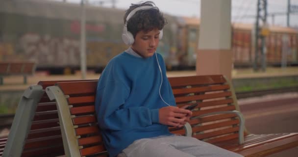 Studenten Koptelefoon Luisteren Naar Muziek Terwijl Wachten Trein Het Station — Stockvideo
