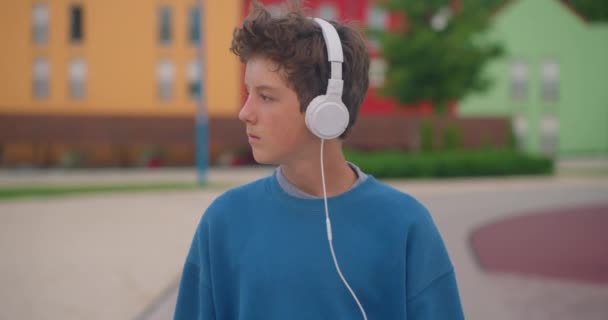 Çekici Genç Sokakta Yürüyor Kulaklıkla Müzik Dinliyor — Stok video