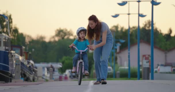 妈妈教女儿骑自行车 快乐的家庭童年梦想的概念 妈妈和小女儿在公园里学习骑自行车 快乐的家人在户外观看阳光 — 图库视频影像