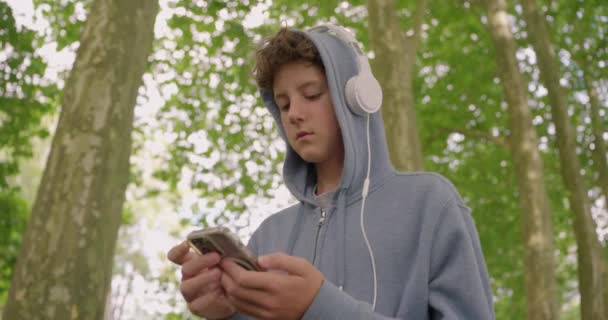 在公园里走来走去听音乐的耳机里 一个沉着的家伙正在接近他 — 图库视频影像