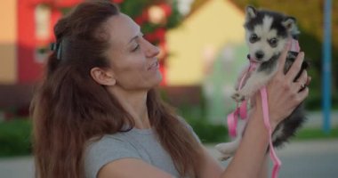 Çekici bir kadın kucağında küçük bir köpek yavrusu tutuyor anın tadını çıkarıyor ve ona sarılıyor..