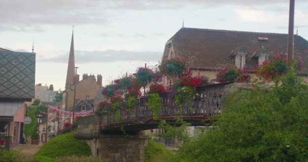 花で飾られた古代の橋 ブルゴーニュのヨンヌ川の近代フランスの都市ミゲンヌ 市内には近代的な建築物とロラチェ ミゲンヌ鉄道駅がある — ストック動画