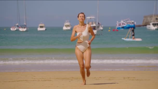Sportowa Dziewczyna Białym Stroju Kąpielowym Biegnie Ciepłym Piasku Jachty Tle — Wideo stockowe
