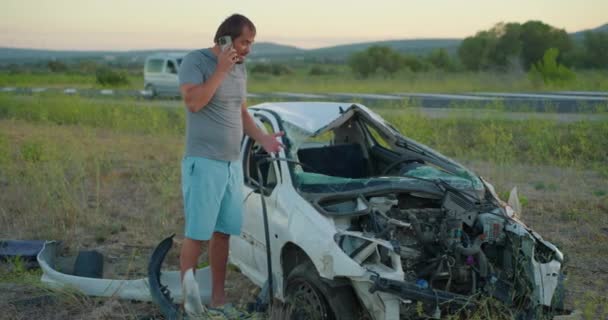 自動車事故の後 車の近くにいた男が救助サービスを呼び出し 感情的に事件を報告する — ストック動画