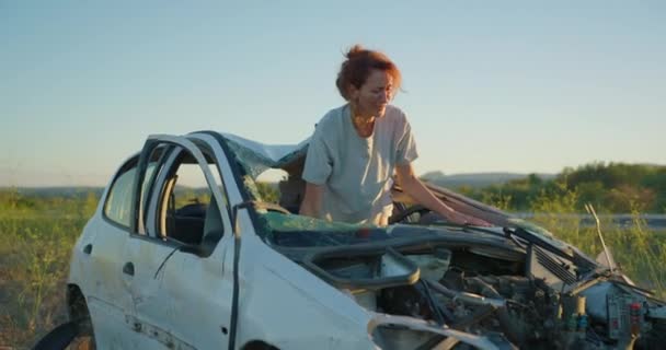 女性は自動車事故の後 荒廃した車に座り ショックとストレスの状態で難破車から脱出しようとします — ストック動画