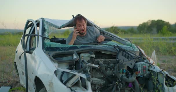 一个男子坐在车里 在车祸中被毁 他试图打电话给保险公司寻求帮助 处于紧张和震惊状态的人 — 图库视频影像