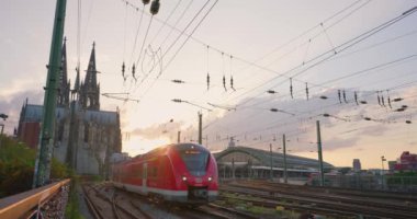 Köln 'deki merkez istasyonda tren trafiği. Şehir görüntüsü oluşturuluyor. Köln 'ün merkezinde günbatımı var..