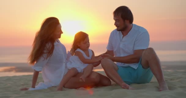 Супружеская Пара Дочерью Сидящей Берегу Океана Золотые Часы Наслаждается Временем — стоковое видео