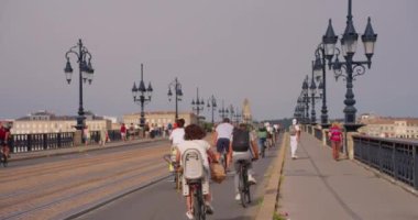 Bordeaux, Fransa, 20 Ağustos 2023: Fransa Bordeaux sokaklarında Pont de Pierre köprüsünü bisikletle geçen turistler.