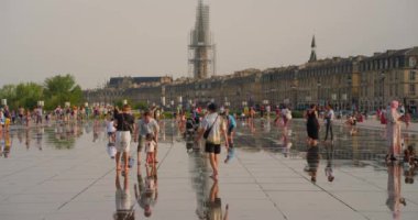 Bordeaux, Fransa, 20 Ağustos 2023: Place ve Palais de la Bourse ve Miroir deau Fransa 'da, antik çağdaş mimariyle tanışır. Sıcak havadaki insanlar merkez meydandaki suyla serinliyor..