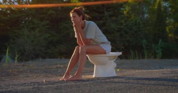 Kadın Gün Batımının Arka Planında Tuvalette Oturuyor — Stok video