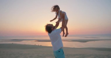 Bir baba gün batımında, arkasında okyanus olan güzel kızını bırakır. Mutlu babalık kavramı ve çocukların neşesi..