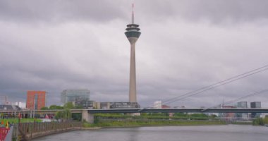 Arka plandaki uzun gözlem kulesi Düsseldorf 'un ana ilgi alanlarından biridir. Almanya 'da şehrin kurulumu, Ren nehri üzerindeki köprüyle ufuk çizgisi - Avrupa manzarası.
