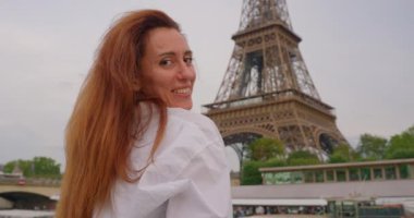 Gülümseyen turist kadın ünlü Eyfel Kulesi 'nin simgesine bakıyor. Eyfel Kulesi yakınlarındaki Seine Nehri 'nde bir turist gemisinde tekne gezisi..