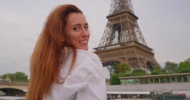 Gülümseyen turist kadın ünlü Eyfel Kulesi 'nin simgesine bakıyor. Eyfel Kulesi yakınlarındaki Seine Nehri 'nde bir turist gemisinde tekne gezisi..