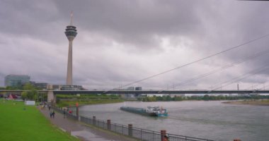 Arka plandaki uzun gözlem kulesi Düsseldorf 'un ana ilgi alanlarından biridir. Almanya 'da şehrin kurulumu, Ren nehri üzerindeki köprüyle ufuk çizgisi - Avrupa manzarası.