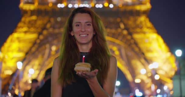 エッフェル塔の近くの街パリで誕生日を祝う ホリデーケーキで大切な願いとろうそくを吹くハッピーなワクワクする女性 すべての女性の誕生日を夢見る — ストック動画