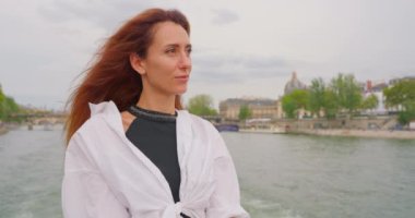 Turist gemisiyle gezen bir kız Seine nehri boyunca Paris manzarasının tadını çıkarıyor..