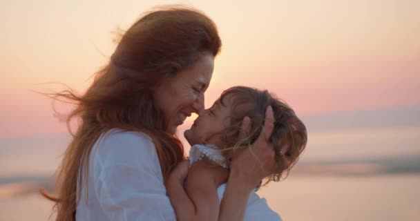 母親は 太陽の背景に彼女の腕を保持しながら 彼女の小さな娘の鼻で遊んでいます 母親のコンセプト 一緒に時間を過ごす — ストック動画