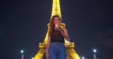 Eyfel Kulesi yakınlarında mum üfleyerek yıl dönümü kutlamaları sırasında ışık saçan kıvırcık saçlı, çekici, neşeli kadının yakın çekimi. Tatil boyunca mutlu kadın portresi.