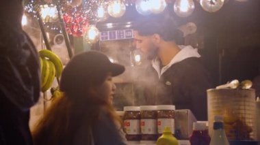 Paris, Fransa, 09 Aralık 2023, Paris 'teki Şanzelize' de akşam yemeği. Turistler arasındaki Noel havası kışın sıcak bir içecek satın alıyor. Noel ışıkları, parıltılı süslemeler..