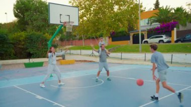 Spor ve aile dostluğu. Dışarıda basketbol oynayan çok nesilli bir aile. Aile boş zamanlarını birlikte spor yaparak ve basketbol sahasında basketbol oynayarak geçirir..