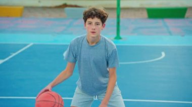 Ağır çekim sokak basketbolu. Basketbol antrenmanı yapan bir çocuk. Genç basketbol oynar. Sağlıklı yaşam tarzı ve hobi anlayışı. Basketbol topuna vuran tatlı bir çocuk..