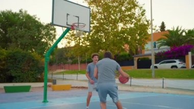 Spor ve aile dostluğu. Dışarıda basketbol oynayan çok nesilli bir aile. Aile boş zamanlarını birlikte spor yaparak ve basketbol sahasında basketbol oynayarak geçirir..